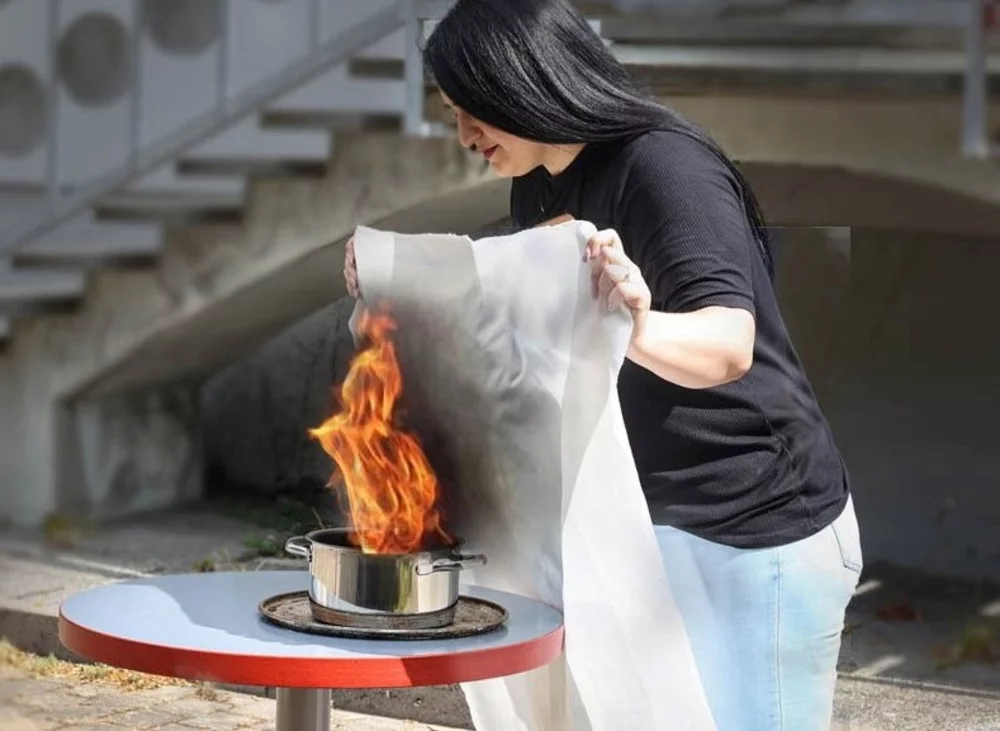 Frau Versucht brennenen Kochtopf mithilfe einer Löschdecke zu löschen. Hier sind besondere Löschtechniken erforderlich